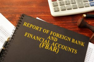 A ledger notebook on a desk titled "Report of Foreign Bank and Financial Accounts (FBAR)"