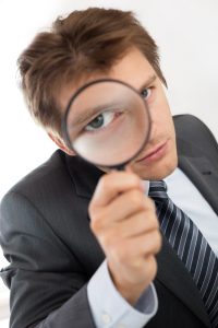 A businessman looking through a magnifying glass