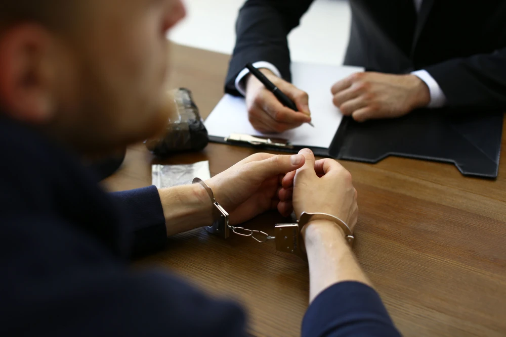 Arrested Man sitting with Criminal Tax Defense Lawyer